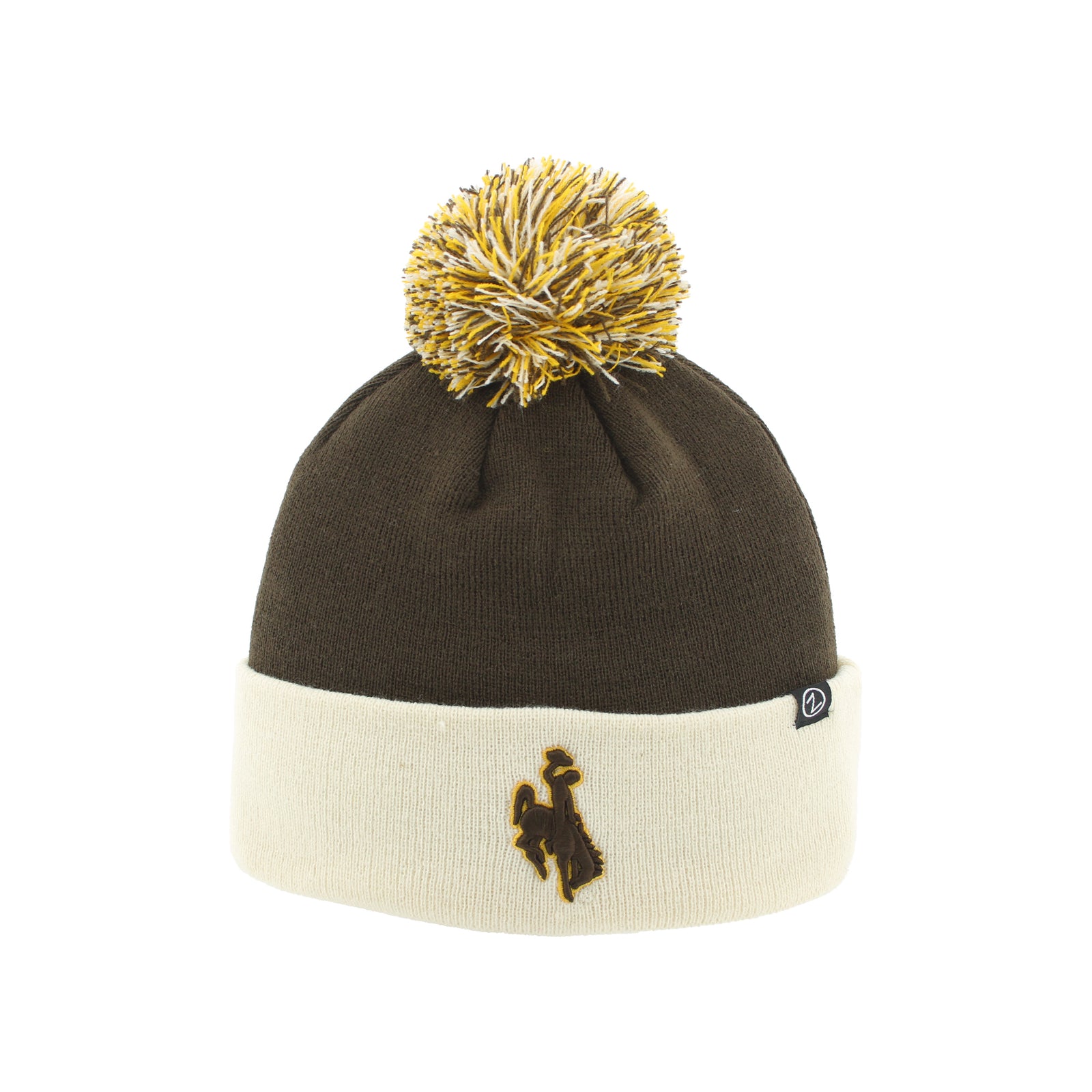 A knit pom-pom beanie hat in dark brown and cream, featuring a gold embroidered logo on the cuff and a gold and cream pom-pom on top, shown against a plain white background.