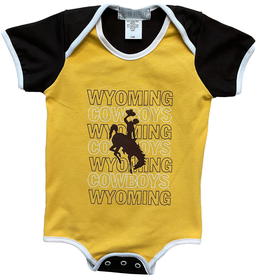gold, brown and white short sleeve onesie. design on front chest, wyoming, in brown, cowboys under in white, repeated to bottom. brown bucking horse over lapping center of design