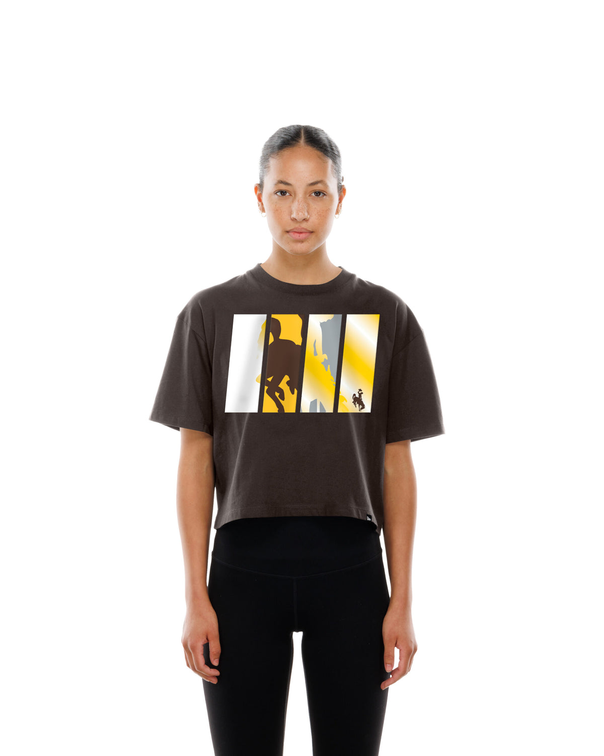 model wearing cropped brown tee with big design cetner chest. design is 4 pillars with bucking bucking horse in them. design has white brown and gold