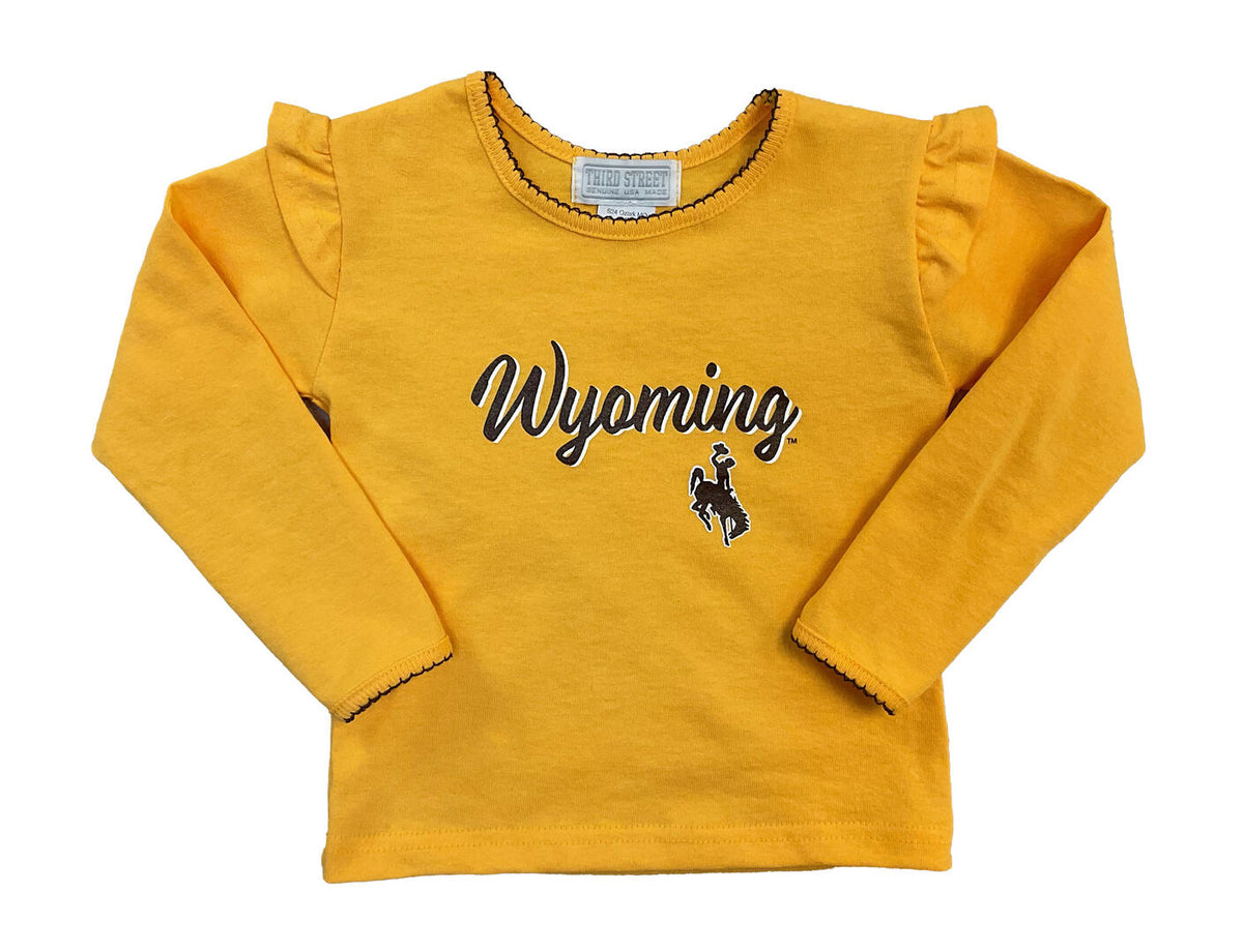 gold kids long sleeve tee with decorative stitching around neck and wrists, with ruffles on shoulder. Wyoming in brown script with white outline and bucking horse under Wyoming