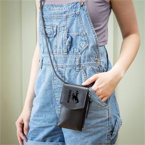 woman standing with black leather crossbody on. has wyoming and bucking horse on flap of the crossbody