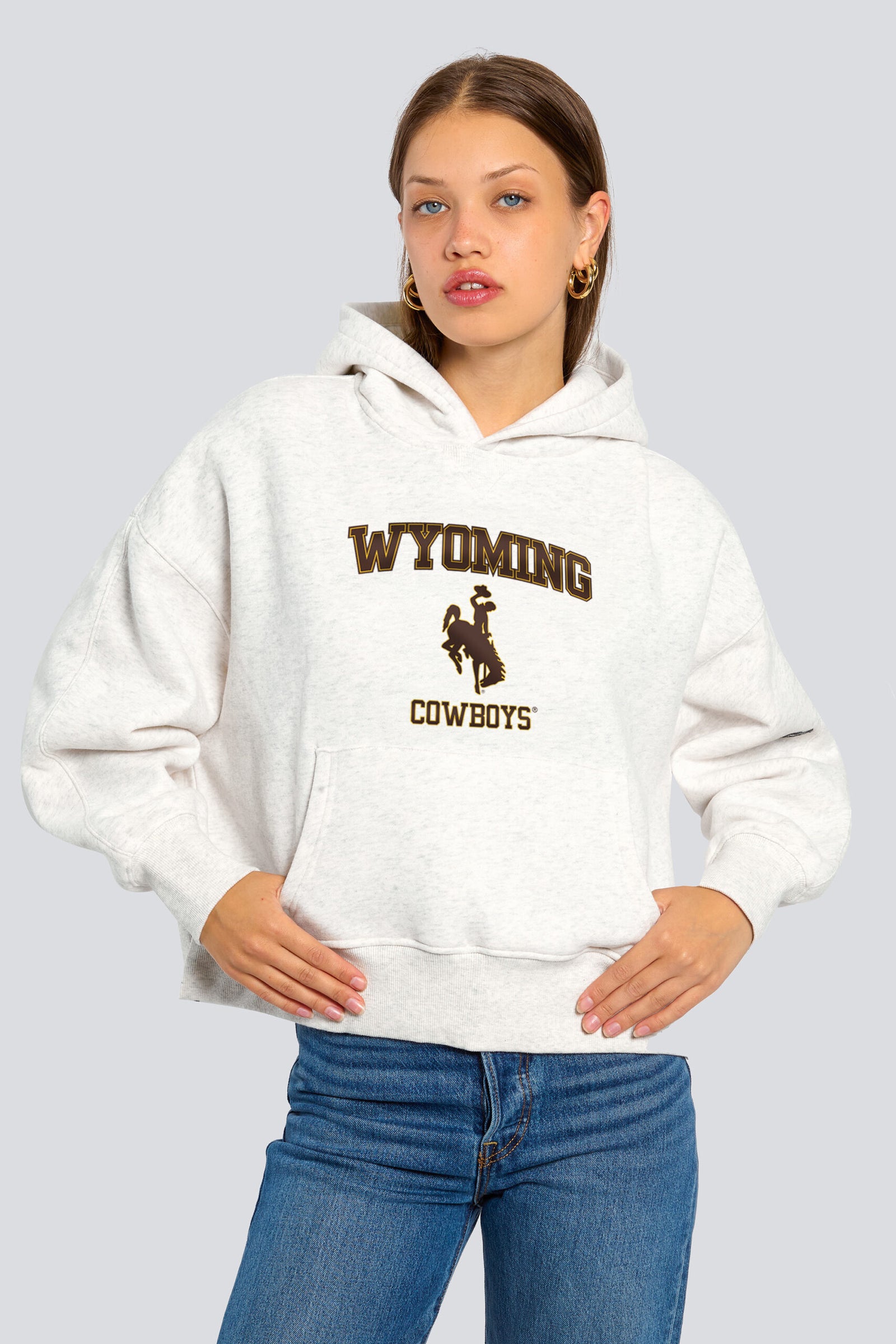 white women's hooded sweatshirt with brown design center chest. design is wyoming lettering with brown bucking horse below and small cowboys lettering below that.