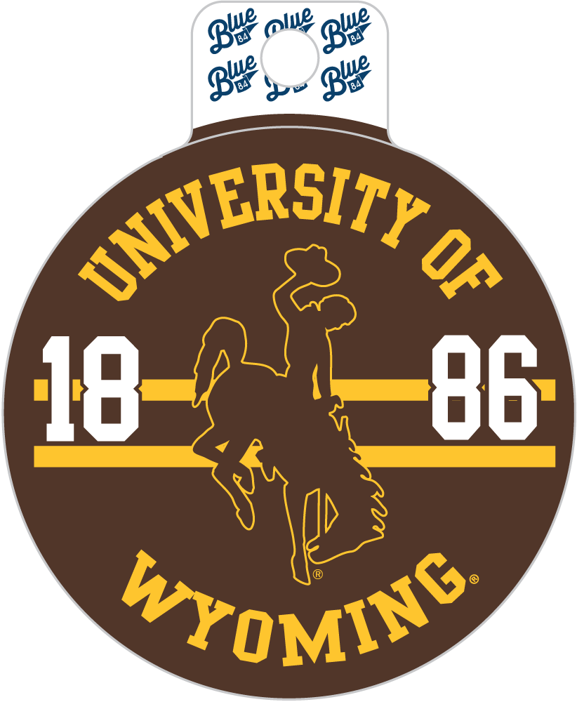 A round brown and yellow University of Wyoming decal or sticker with a white hanging tab at the top. The design features the text 'UNIVERSITY OF WYOMING', the year '1886', and a silhouette of a cowboy on a bucking horse, with 'Blue' logos printed on the top tab.