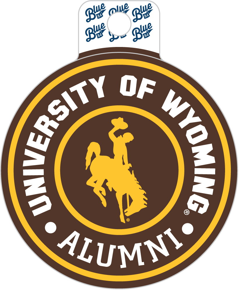 A circular University of Wyoming Alumni sticker or decal with a white hanging tab at the top. The design features a brown outer ring with white text reading 'UNIVERSITY OF WYOMING ALUMNI,' a yellow inner ring, and a yellow silhouette of a cowboy on a bucking horse in the center.