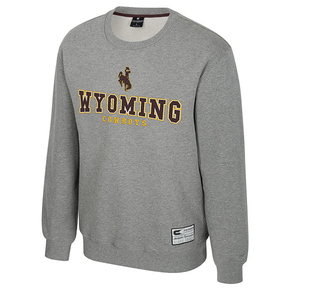 A heather gray crewneck sweatshirt featuring 'WYOMING COWBOYS' printed across the chest in brown and gold, with a cowboy riding a bucking horse graphic above the text. A small Nike brand tag is visible near the lower hem.