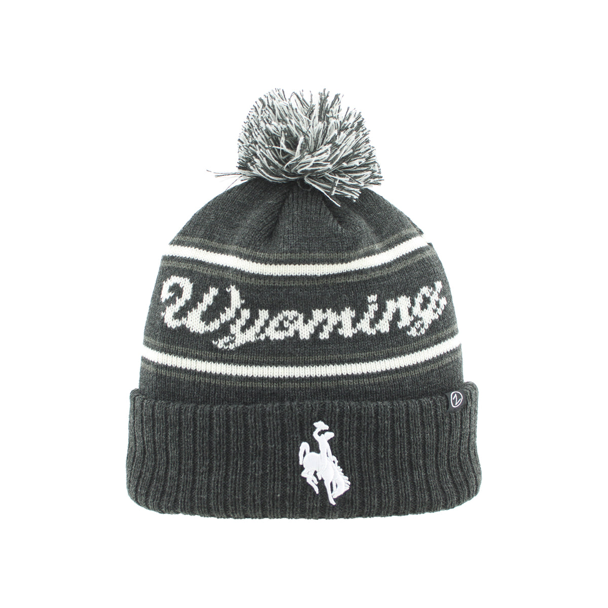 A dark gray knit beanie hat with a white pom-pom, featuring the word 'Wyoming' knitted across the upper section and a white cowboy rider logo on the folded cuff.