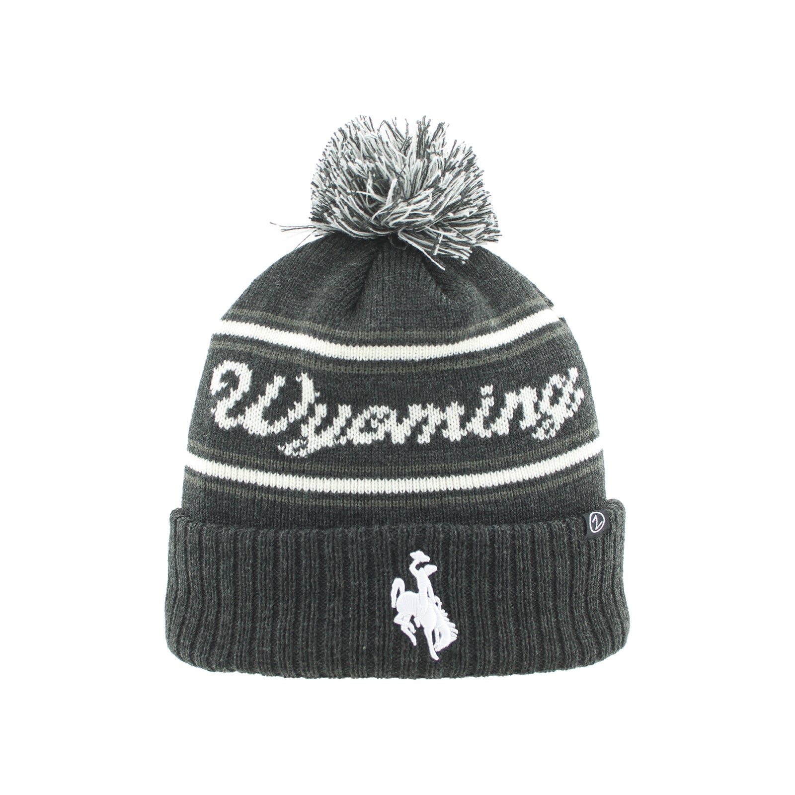 A dark gray knit beanie hat with a white pom-pom, featuring the word 'Wyoming' knitted across the upper section and a white cowboy rider logo on the folded cuff.