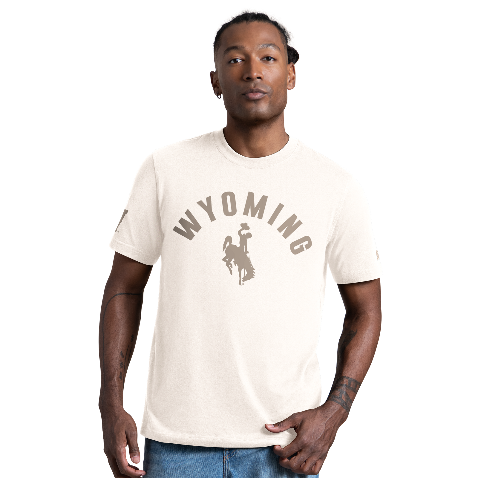 Gentleman wearing a cream short sleeve shirt with wyoming and bucking horse logo center chest in a tan color. 