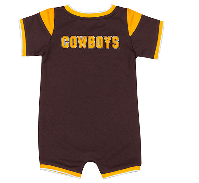A short-sleeve baby romper in dark brown with yellow trim on the collar, sleeves, and leg openings, featuring the word 'COWBOYS' printed across the chest in yellow block letters with a white outline.