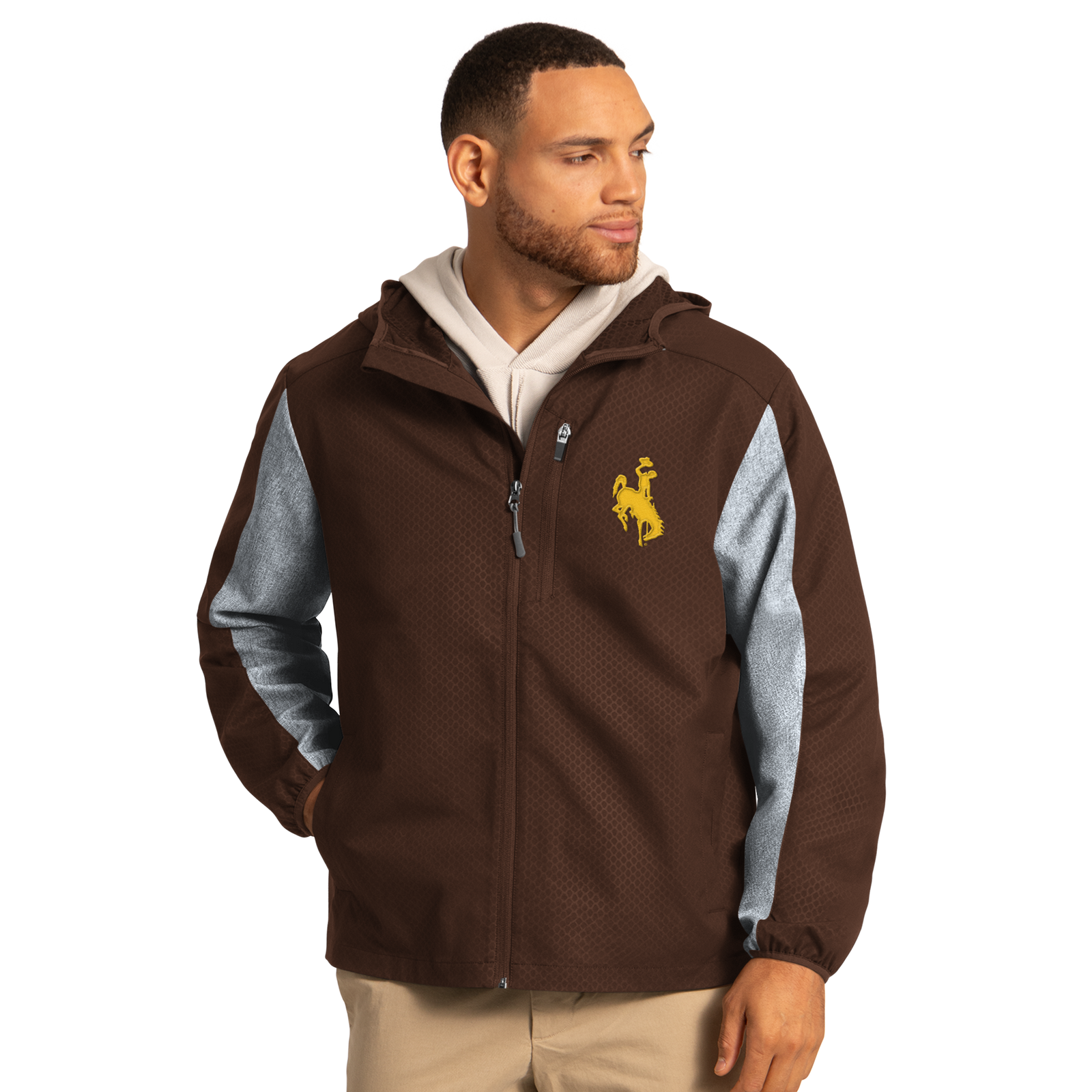 Man wearing a brown and grey light weight jacket with gold bucking horse logo on left chest. Has khaki pants on. Pictured on a white background.