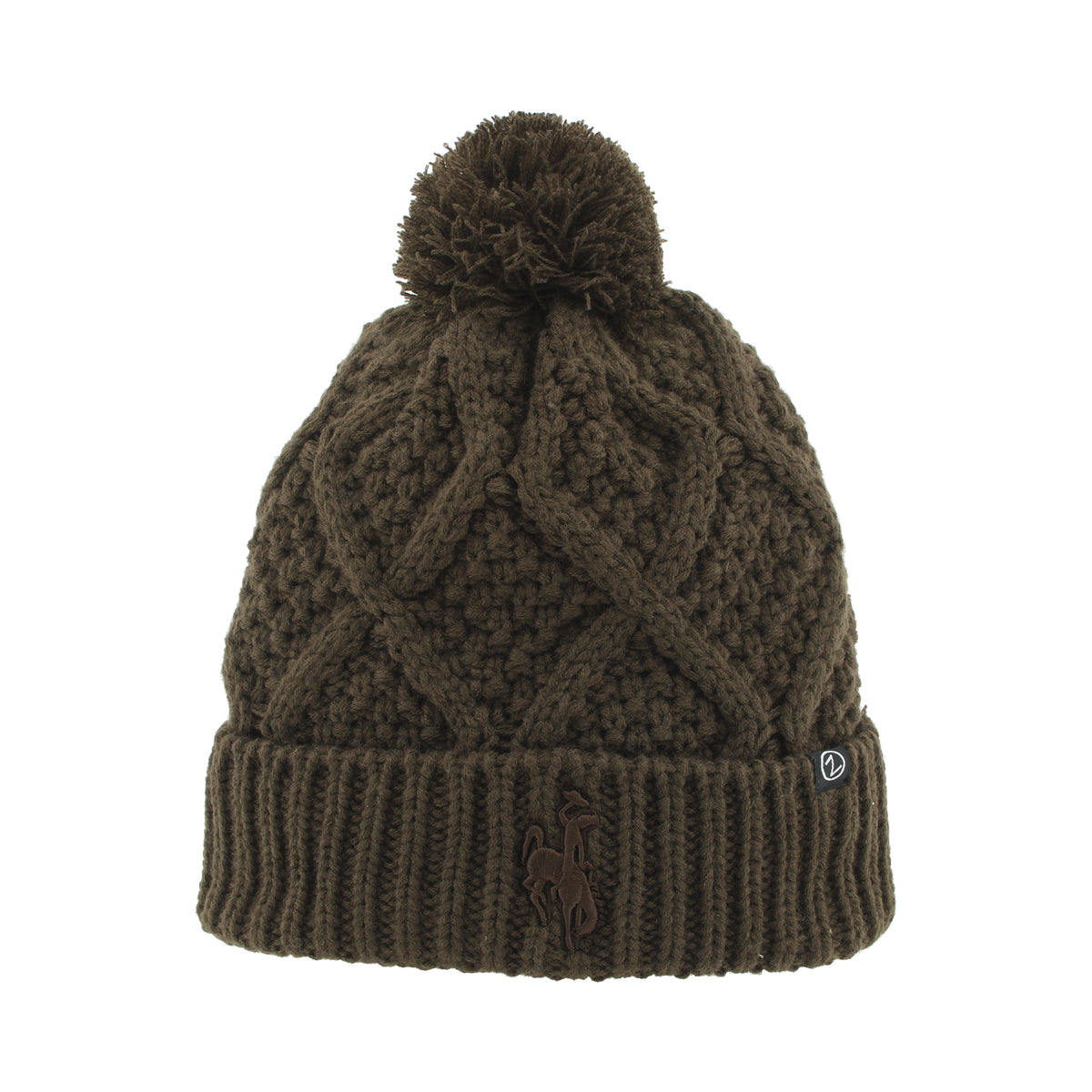 An brown cable-knit pom-pom beanie with a ribbed cuff, featuring a small embroidered horse logo on the front and a small white brand tag on the side.