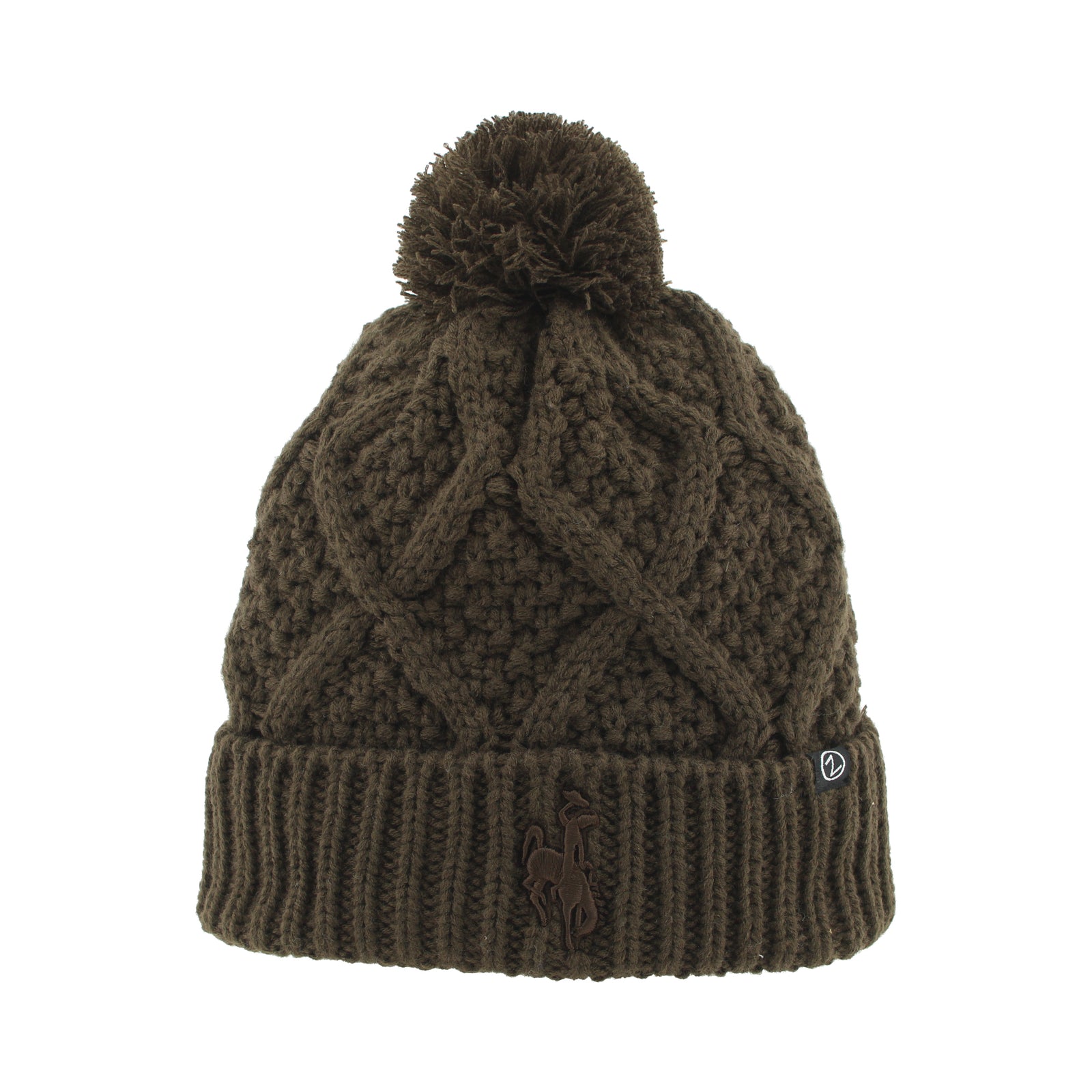 An brown cable-knit pom-pom beanie with a ribbed cuff, featuring a small embroidered horse logo on the front and a small white brand tag on the side.