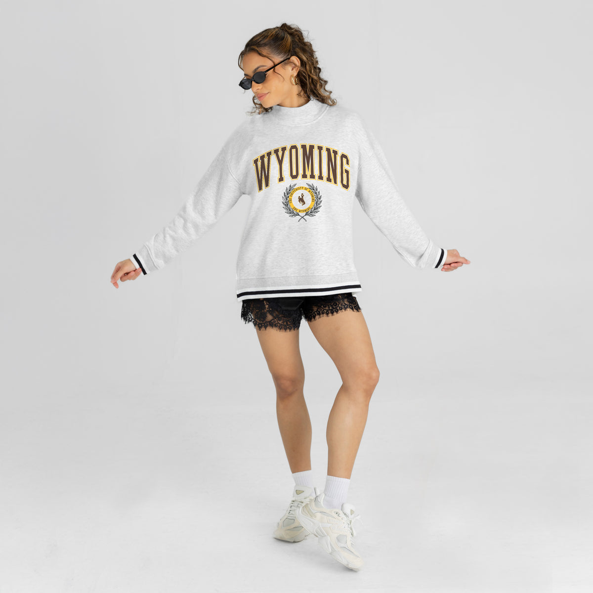 Person wearing a white 'Wyoming' sweatshirt on a light gray background