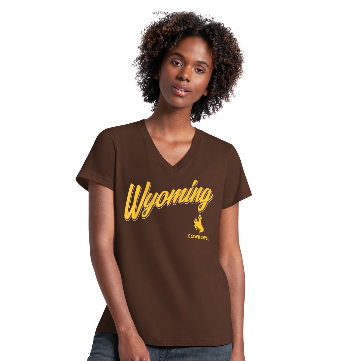 Woman with dark curly hair posing with a brown tee shirt on that says 'wyoming cowboys' in gold with bucking horse logo. 