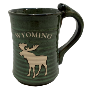 green ceramic mug with varying darkness, design is tan word Wyoming above tan moose, large handle on right of mug