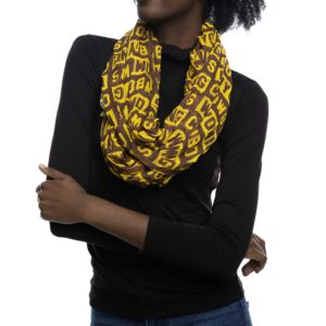 model wearing women's gold, lightweight infinity scarf. scarf has words Wyoming Cowboys printed all over in brown and gold