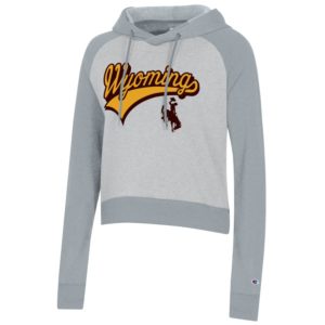 women's short hooded sweatshirt. light grey body, with dark grey sleeves and hood. Word Wyoming printed in gold in script font with tail. bucking horse printed below on front