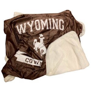 cream sherpa blanket, with smooth brown side. Wyoming Cowboys and bucking horse on brown side of blanket in white