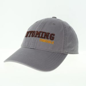 dark grey garment washed, adjustable hat. Word Wyoming embroidered in brown on front, with word Cowgirls embroidered in gold below