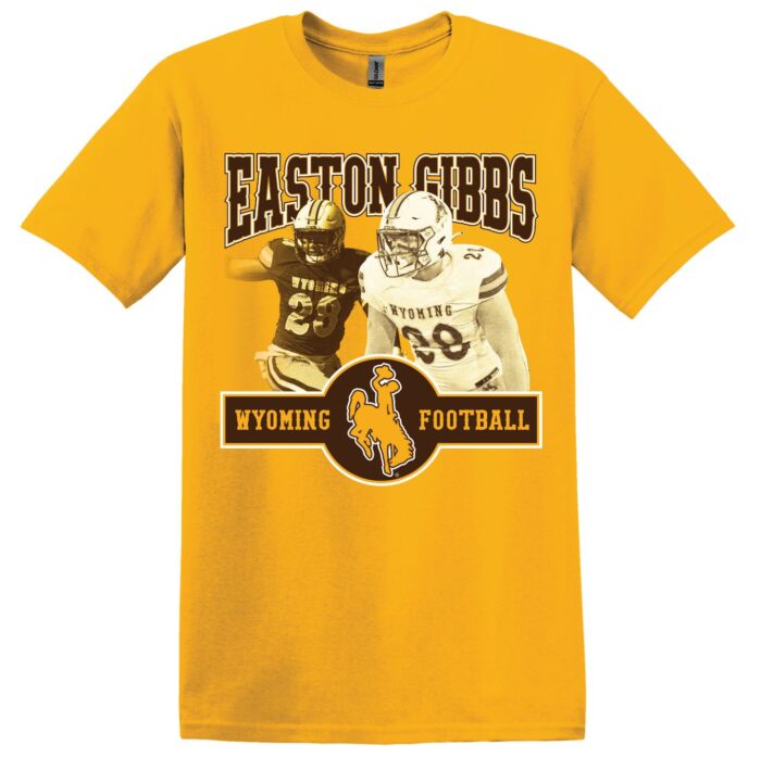 gold short sleeved tee with design on front center. Design is name Easton Gibbs in brown with photo of him in football uniform below. Below images is slogan Wyoming Football in brown