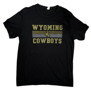 black short sleeved shirt, design is word Wyoming in white block letters outlined in gold, gold and yellow lines with gold bucking horse in center above word cowboys in white block letter outlined in gold