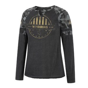 charcoal women's long sleeve tee with grey camo sleeves, notched neck line, design is tan circle with vertical stripes on top half stars and bucking horse in bottom half, banner with word Wyoming through middle