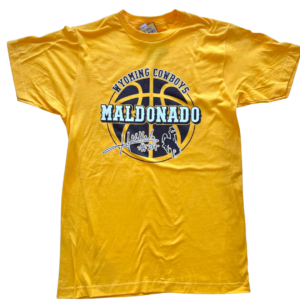 gold short sleeve tee. design is brown word Wyoming Cowboys arched over brown basketball, white word Maldonado across center, Maldonado signature with #24 in white below, next to brown bucking horse
