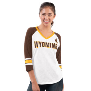 Women's white long sleeve with brown 3/4 sleeves, design is brown word Wyoming gold outline, brown bucking horse gold outline, gold v neck detail, gold stripes on sleeves