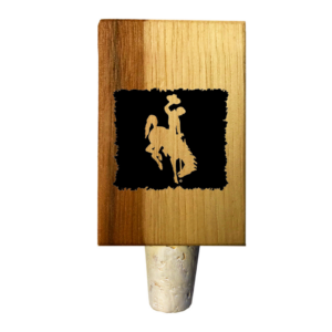 Wooden bottle stopper, design is black square with bucking horse cutout exposing wood below, cork bottom