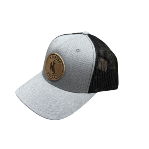 Grey hat with black mesh backing, design is brown leather circle with word Wyoming above bucking horse above word cowboys