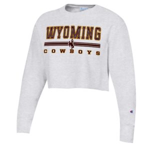 white women's crewneck cropped sweatshirt. Design on front, Wyoming in brown with white and gold outline, brown stripe and bucking horse under Wyoming. Cowboys in brown with gold outline below stripe.