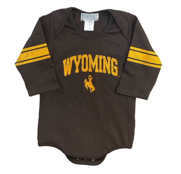 brown long sleeve onesie with design on front and sleeves. On front Arced, distressed, Wyoming with bucking horse in gold. Sleeves have gold arm bands around the elbow.