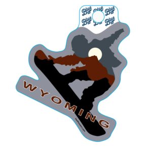 Snowboarder shaped decal, design is blue, brown, and black mountain range outlines with moon above brown word Wyoming