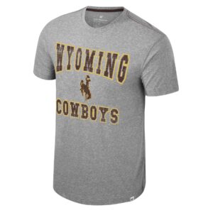 light grey short sleeve t-shirt with distressed, wyoming at neckline, bucking horse under, and cowboys near bottom center. all text is brown with gold outline
