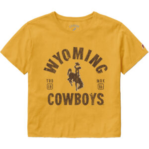 Gold short sleeve crop t-shirt. Design is center chest, wyoming at top, arced, with brown bucking horse under. Cowboys at bottom of design. text is bold brown.