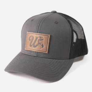 Black snapback adjustable hat with patch on front. Patch is brown with cursive W and bucking horse with state flag.