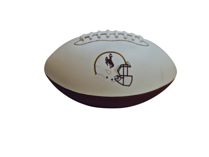 White and brown full-size football. white grip with a white football helmet with brown bucking horse on left and wyoming in brown and gold on right side
