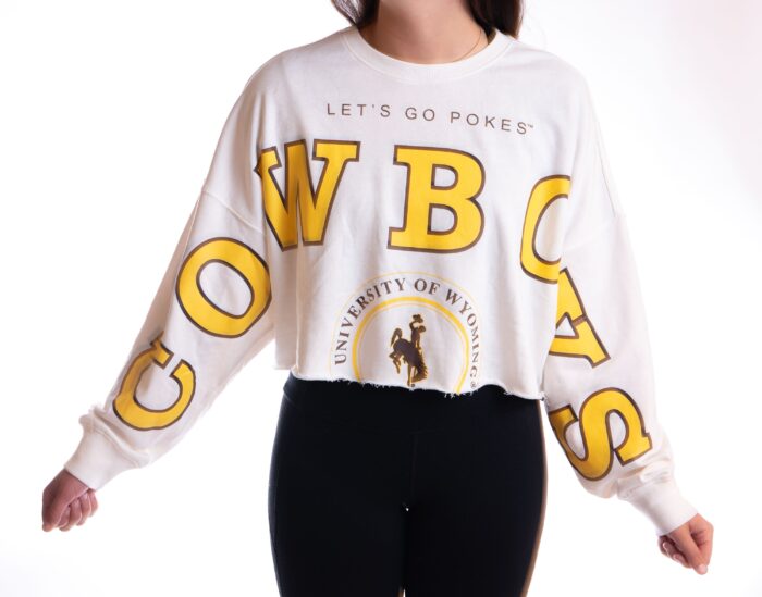 white cropped crewneck sweatshirt with design stretching from right sleeve, across chest, down left arm. Design is cowboys in gold with brown outline, lets go pokes above on center chest