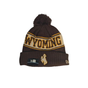 brown beanie with brown pom and cuff. around center head, lighter brown back with Wyoming on front and cowboys on back in dark brown with gold outline. white embroidered bucking horse on cuff