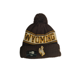 brown beanie with brown pom and cuff. around center head, lighter brown back with Wyoming on front and cowboys on back in dark brown with gold outline. white embroidered bucking horse on cuff