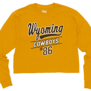 gold womens crop long sleeve with design centered. design is brown wyoming script with white outline, with cowboys in white below and brown 1886 below that