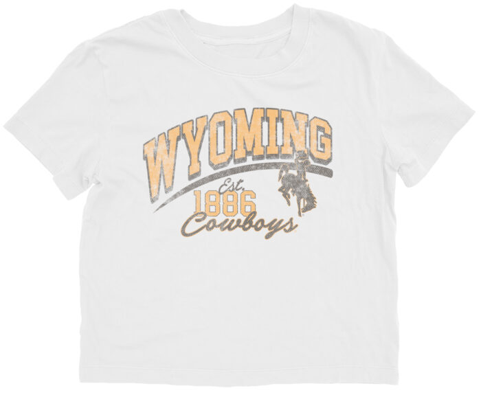 white womens crop tee with design centered. design is gold wyoming lettering with brown outline and est. 1886 and script cowboys below and bucking horse left centered