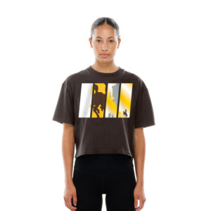 model wearing cropped brown tee with big design cetner chest. design is 4 pillars with bucking bucking horse in them. design has white brown and gold