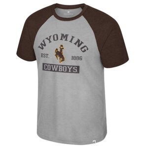 grey body with brown sleeve tee shirt with design center chest. design is arched wyoming with brown bucking horse below and est on left and 1886 on right with cowboys below