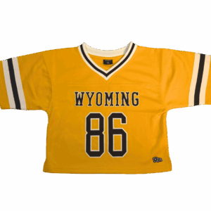 gold cropped women's jersey. has brown wyoming lettering on front with big 86 below. has brown and white stripes on the sleeves and on neck