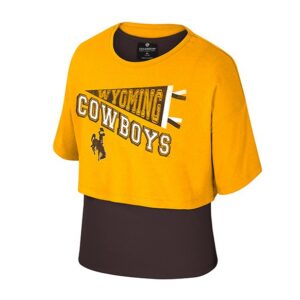 girls double layered shirt. has tight brown layer on bottom with gold cropped layer on top. design is all over front of shirt. design is wyoming in a pennant with cowboys below and bucking horse below that. all in brown white and gold.
